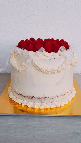 Bolo branco com laços e framboesas por cima
